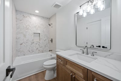 Modern bathroom featuring sleek marble tile, dual sinks, and a spacious tub for relaxation.
