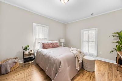 Bright and inviting bedroom featuring natural light, warm hardwood floors, and cozy, modern decor.