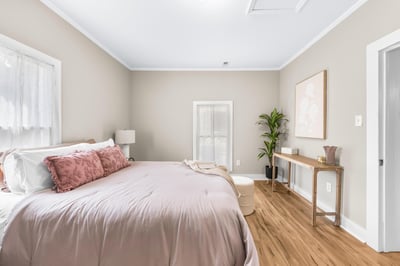 Bright and spacious bedroom featuring a large window, cozy decor, and natural wood accents throughout.