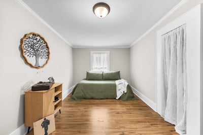 Cozy bedroom featuring natural wood flooring, ample light, and a peaceful minimalist design.