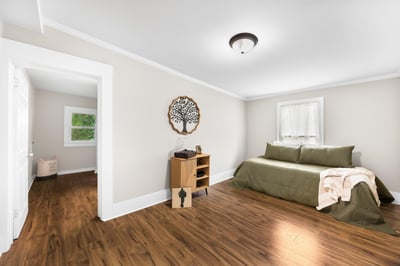 Bright and airy bedroom features warm wood floors, natural light, and a cozy atmosphere perfect for relaxation.