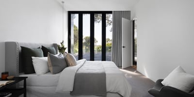 Stylish bedroom featuring large windows, modern decor, and serene views, perfect for relaxation and comfort.