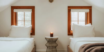 Cozy twin bedroom featuring natural light, unique decor, and a warm ambiance for restful stays.