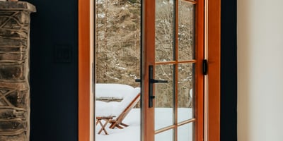 Bright entryway featuring a wooden door opening to a snowy outdoor retreat, perfect for winter getaways.