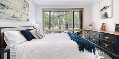 Spacious bedroom featuring large windows, natural light, and a view of lush outdoor greenery.