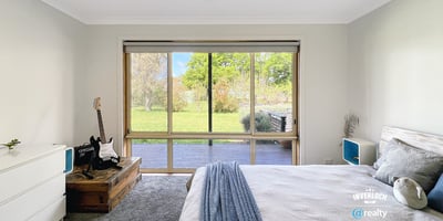 Bright bedroom featuring a large window with garden views, complemented by modern furnishings and cozy atmosphere.