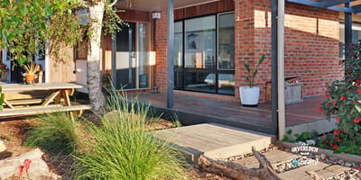 Contemporary home featuring expansive windows and an inviting outdoor space surrounded by lush greenery.