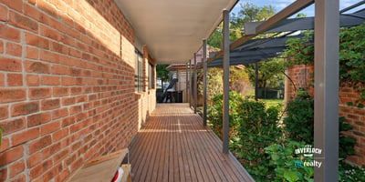 Inviting walkway lined with brick and greenery, leading to a secluded outdoor living space.