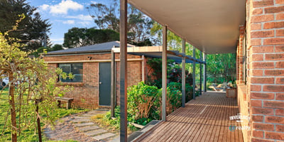 Spacious covered porch leads to a well-maintained garden, offering a welcoming entry to this unique property.