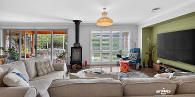 Spacious living area with a cozy stove, large windows, and bright natural light throughout.