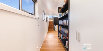 Bright and inviting hallway features built-in shelving, leading to a spacious upper-level living area.