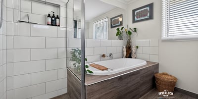 Modern bathroom featuring a spacious tub, glass shower, and organized space with natural light.
