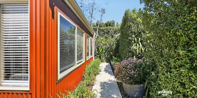Lush landscaping surrounds this vibrant home, featuring a welcoming pathway and abundant greenery for outdoor enjoyment.