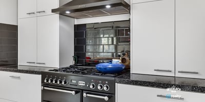 Modern kitchen featuring sleek cabinetry, a gas range, and a striking mirrored backsplash for added depth.