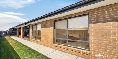 Modern brick home featuring large windows and a spacious yard, perfect for outdoor activities and natural light.