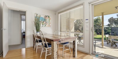 Bright dining area featuring large windows, a spacious table, and easy access to a private outdoor space.