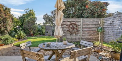 Enjoy outdoor living in this inviting patio, featuring a cozy seating area and lush greenery.