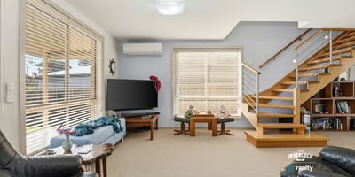 Spacious living area featuring high ceilings, abundant natural light, and modern staircase, ideal for gatherings.