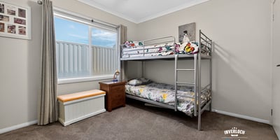 Cozy bedroom featuring a bunk bed, ample natural light, and versatile storage options.