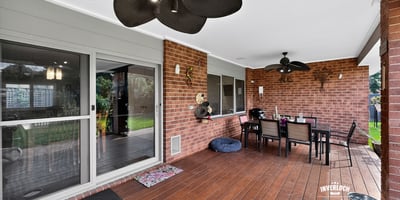 Spacious covered patio perfect for outdoor dining, featuring ceiling fans and a view of the lawn.