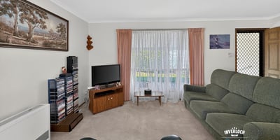 Spacious living room with large windows, offering ample natural light and a cozy atmosphere for gatherings.