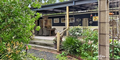 Discover this inviting home with a spacious deck, surrounded by lush landscaping and vibrant greenery.