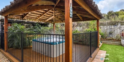 Relax in this private outdoor gazebo featuring a hot tub, surrounded by lush greenery.