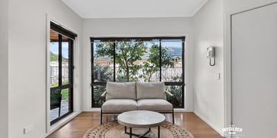 Bright and inviting living space featuring large windows that offer a view of the lush garden.