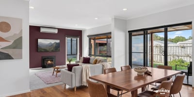 Bright and inviting open-plan living space featuring large windows and a cozy fireplace. Perfect for gatherings.