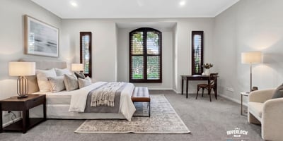Spacious master bedroom featuring large windows, plush carpeting, and a cozy reading nook.