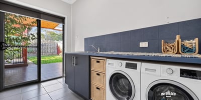 Bright laundry room featuring modern appliances and direct access to a shaded outdoor area.