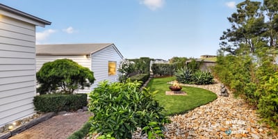 Discover a tranquil outdoor space featuring neat landscaping, unique planting beds, and a cozy fire pit area.