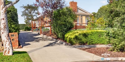 This spacious home features a picturesque landscape, inviting driveway, and ample outdoor space for entertaining.