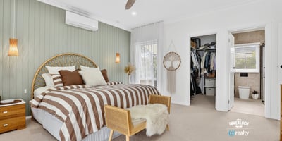 Spacious bedroom featuring unique decor, natural light, and convenient access to an organized closet and bathroom.