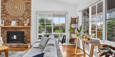 Bright, inviting living space featuring a cozy fireplace and panoramic views of the surrounding gardens.