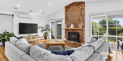 Spacious living area features a cozy fireplace, ample natural light, and direct access to outdoor views.