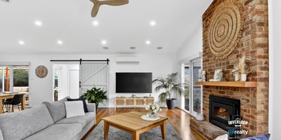 Bright and inviting living space featuring a striking brick fireplace and modern ceiling fan, perfect for gatherings.