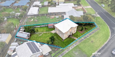 Spacious corner lot with potential for development, featuring a two-story home and ample outdoor space.