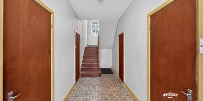 Spacious hallway with wooden doors, leading to a staircase and inviting natural light throughout the space.