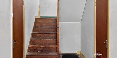 Bright entryway featuring a wooden staircase and dual access doors, perfect for welcoming guests.