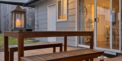 This inviting outdoor space features a wooden dining set and soft lighting, perfect for gatherings.
