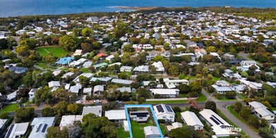 Discover a prime coastal property surrounded by lush greenery and modern homes, just steps from the shoreline.