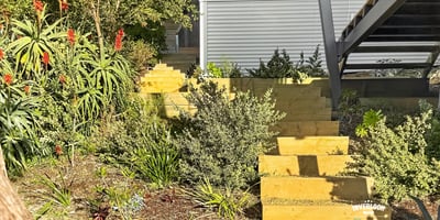 This unique home features a beautifully landscaped garden with inviting wooden steps leading to an open entry.