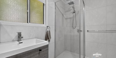 Modern bathroom featuring a walk-in shower and sleek cabinetry, designed for functionality and comfort.