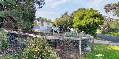 Quaint home nestled among lush greenery, featuring a spacious yard and a peaceful neighborhood setting.