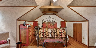 Cozy attic bedroom featuring unique architecture, rustic decor, and ample storage options for personal belongings.