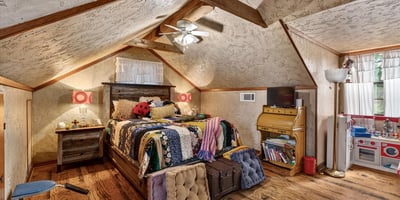 Cozy attic bedroom featuring unique rustic decor, ample natural light, and inviting wooden accents throughout.