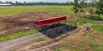 Versatile property featuring a spacious open field with a covered structure, perfect for agricultural or recreational use.