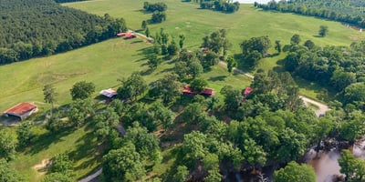 Expansive rural property featuring lush pastures, scenic water views, and multiple outbuildings for versatile use.