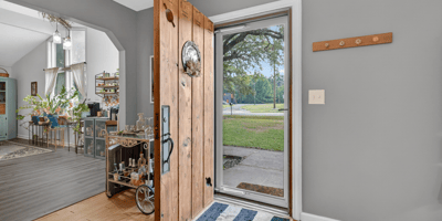 Welcoming entryway featuring a solid wooden door, leading to an inviting, open living space with abundant natural light.